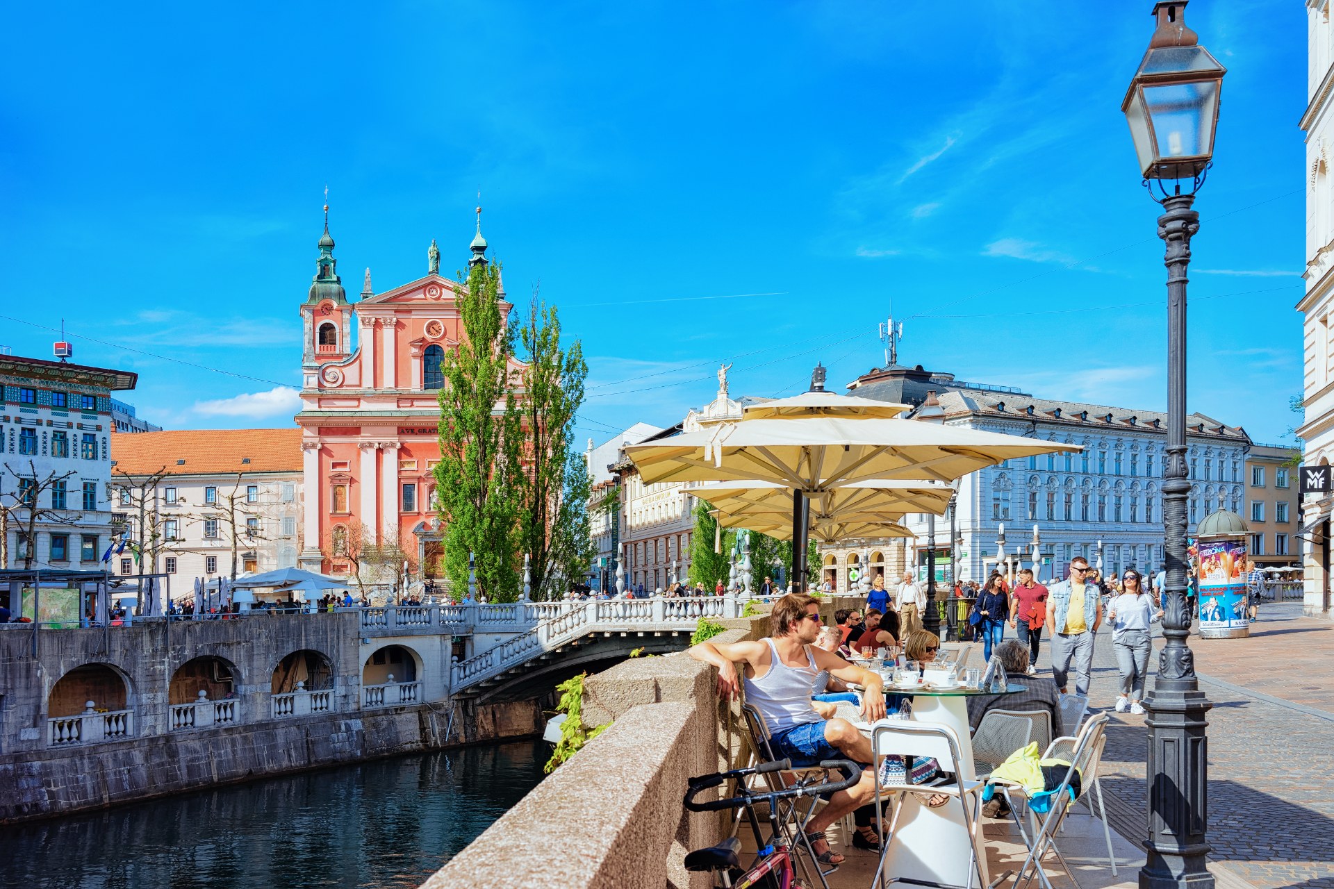 Pessoas numa esplanada na Ponte Tripla, junto ao rio Ljubljanica, em Liubliana
